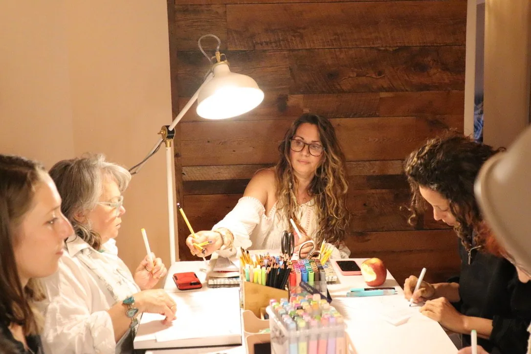 Women seated around a table engaged in archetypal personification through the creative act of collage.
